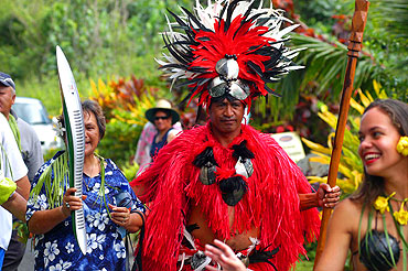 Rarotonga Moko. Dressed in traditional clothing and wearing red to signify the Takitumu district, Rarotonga Moko participates in local relay celebrations.